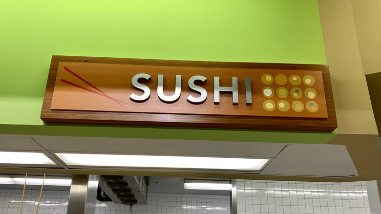 The sushi counter at a Publix, with "Sushi" written on a dark wooden board against a green wall