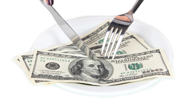 Cutting $100 bills with knife and fork