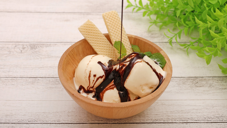 chocolate syrup poured onto ice cream with wafers