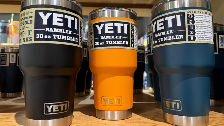 Yeti tumblers in black, orange, and navy blue on display at an REI store