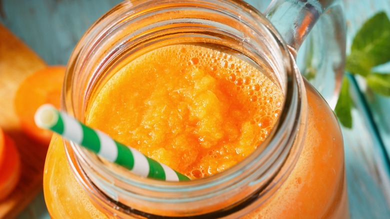 carrot smoothie in jar with straw 