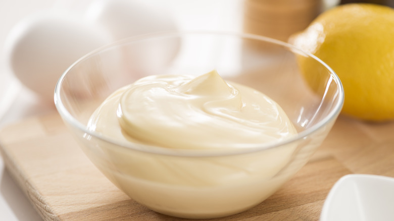A clear glass bowl with whipped homemeade mayonnaise in it