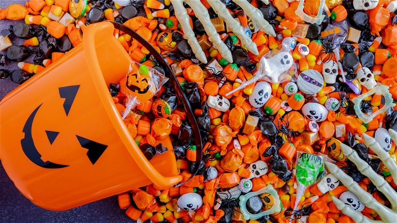 Halloween candy alongside pumpkin bucket 