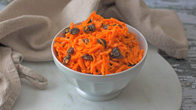 A white bowl filled with carrot raisin salad