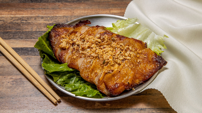 Grilled pork jowl on a white plate with chop sticks