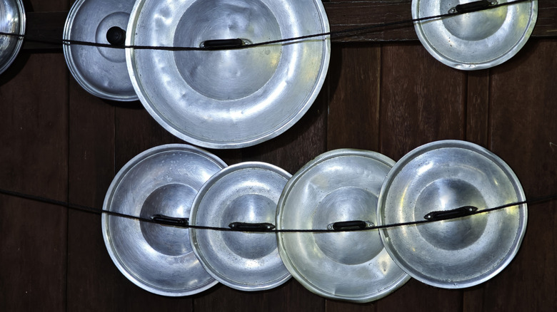 pot lids suspended on string against rustic wall