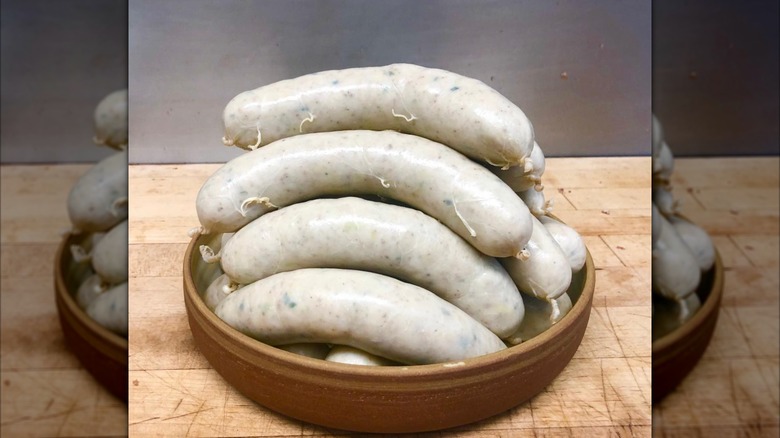 Several white putting sausages stacked in a ceramic bowl