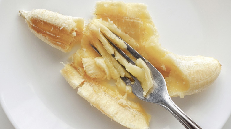 A fork mashes a banana