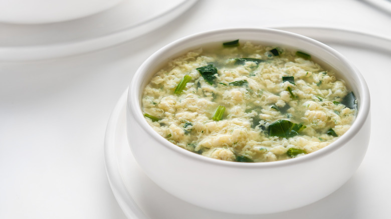 white bowl of stracciatella soup on white table