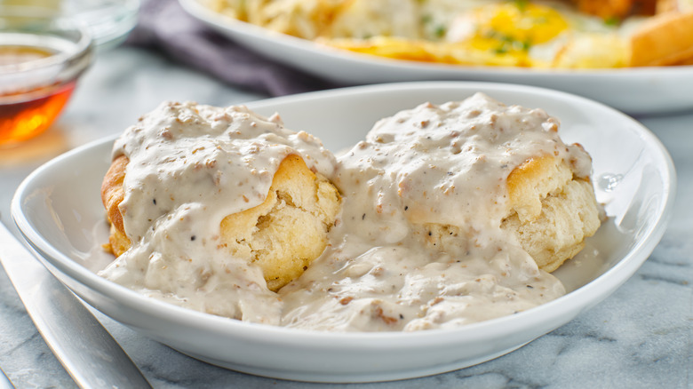 Two biscuits and sausage gravy on white plate
