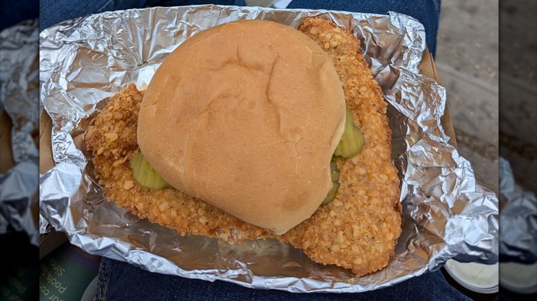 Overhead view of a state fair pork tenderloin sandwich on tinfoil in someone's lap