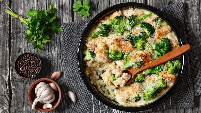 A black dish of chicken divan next to dishes of seasonings