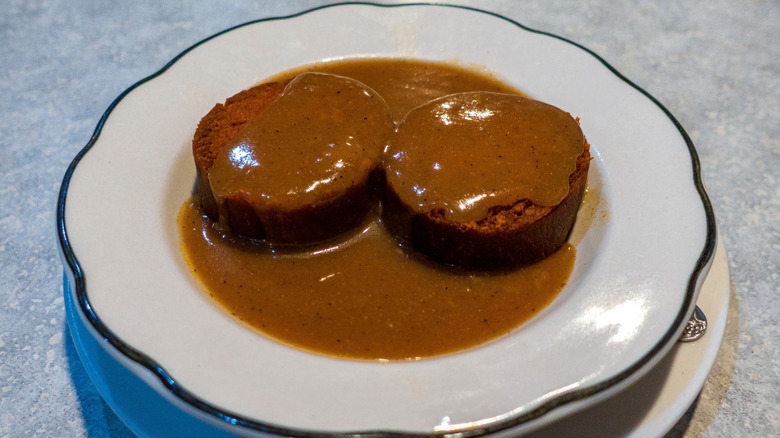 A plate of Kishka, a large sausage chopped in two, smothered in gravy