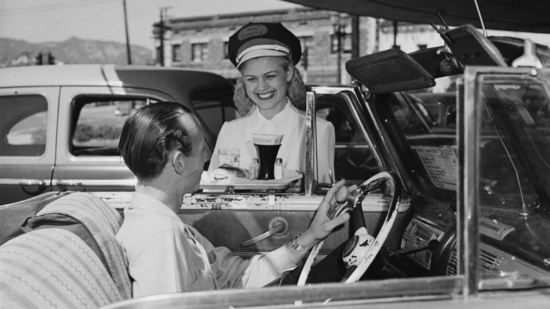 A server at 1970s fast food chain bringing a customer their order