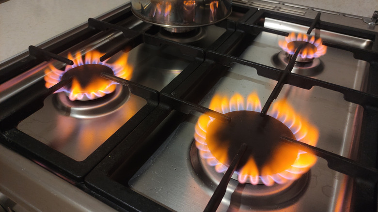 Three burners on a stainless steel gas stove with orange flames