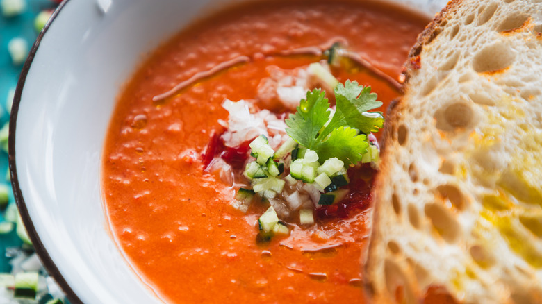 tomato soup in bowl with bread and diced cucumber
