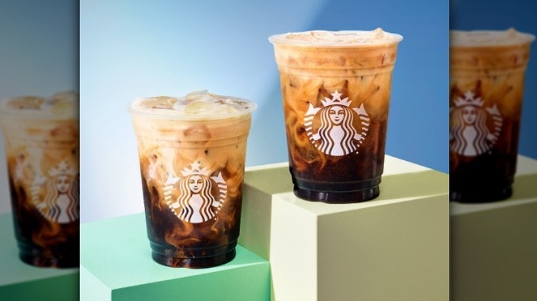 Two shaken espresso drinks with blue background