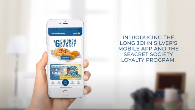Commercial for Long John Silver's mobile app, featuring a hand holding up a phone displaying the app and text saying "Introducing the Long John Silver's Mobile App and the Seacret Society Loyalty Program."