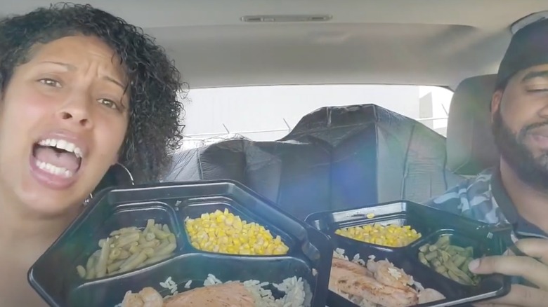 A man and a woman sit in a car, both holding Long John Silver's Grilled Salmon Meal.