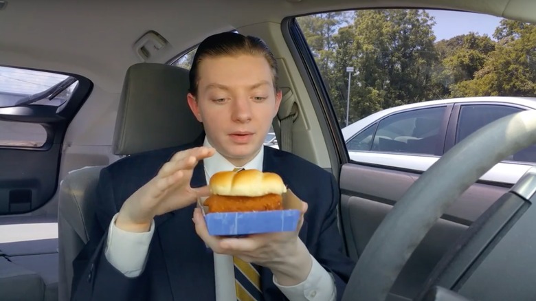 Man sitting in a car, holding a fish sandwich from Long John Silver's.