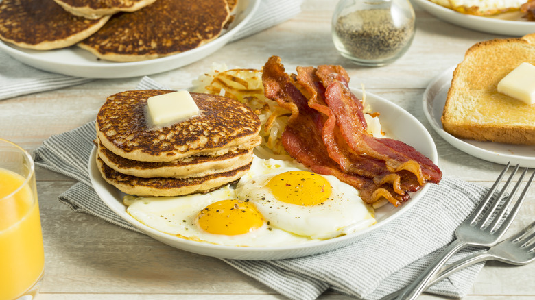 A plate of pancakes, hashbrowns, bacon and eggs