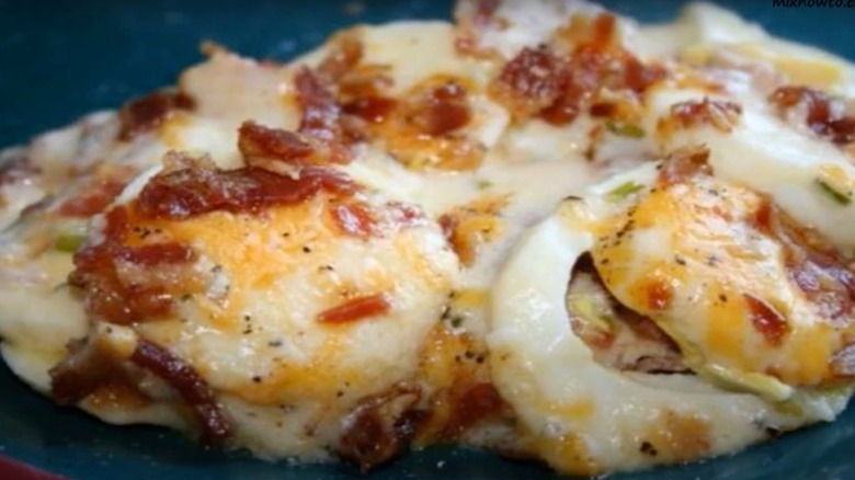 Scalloped eggs sprinkled with chopped bacon