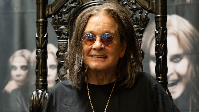 Ozzy Osbourne wearing sunglasses in ornate black chair