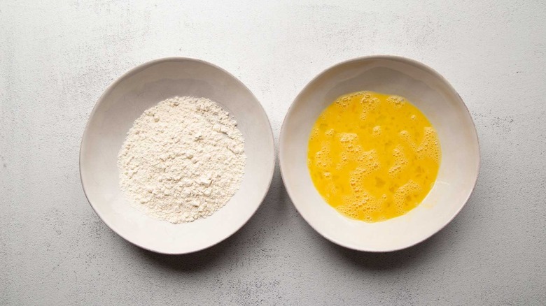 Flour and eggs in white bowls