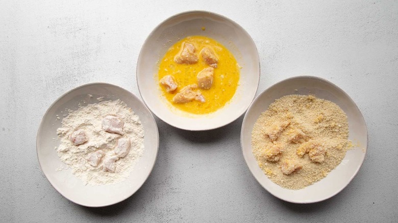 Raw chicken chunks in flour, eggs, and breadcrumbs