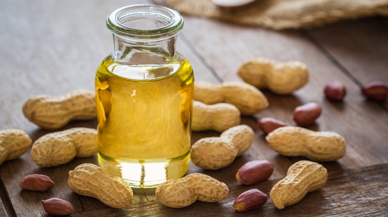 Peanut oil in glass bottle and peanuts on wooden table