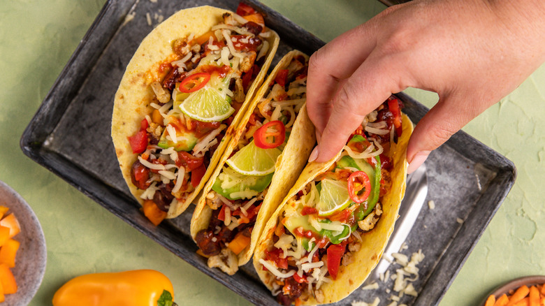 Person placing vegan tacos on tray