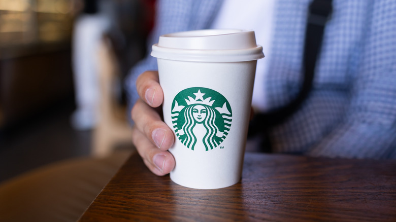 Hand holding paper Starbucks cup