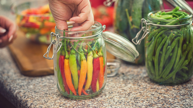 hand in jar of peppers
