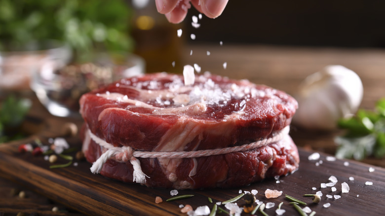 Salt being sprinkled on a filet mignon