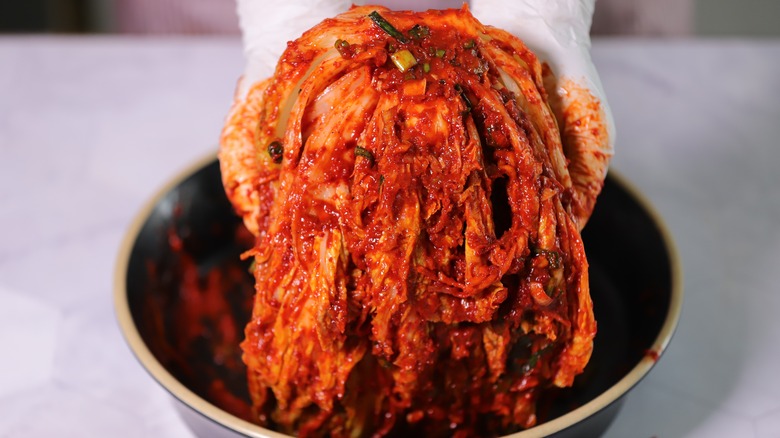 Person wearing gloves holding kimchi