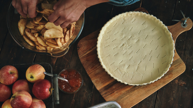 A person preparing an apple pie