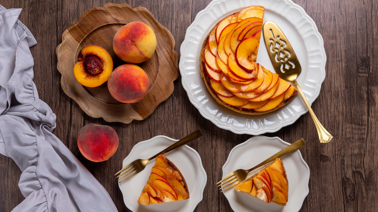 Top down view of a peach tart next to a wooden plate of peaches