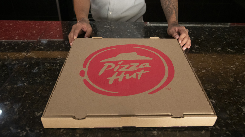 A man holds a Pizza Hut box