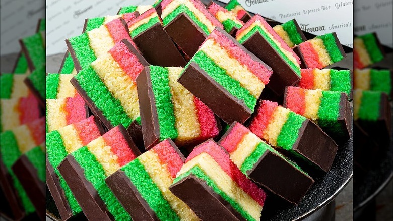 slices of rainbow cake in a tray, covered in chocolate