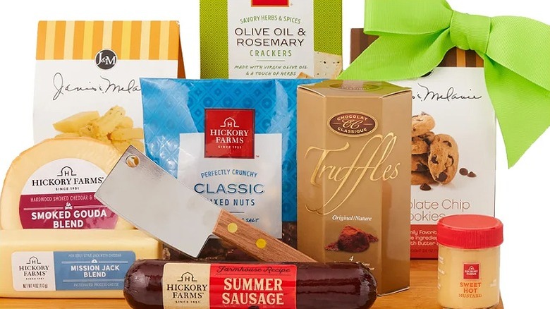 a selection of cheeses, meats, nuts and crackers on a wooden board with a green bow