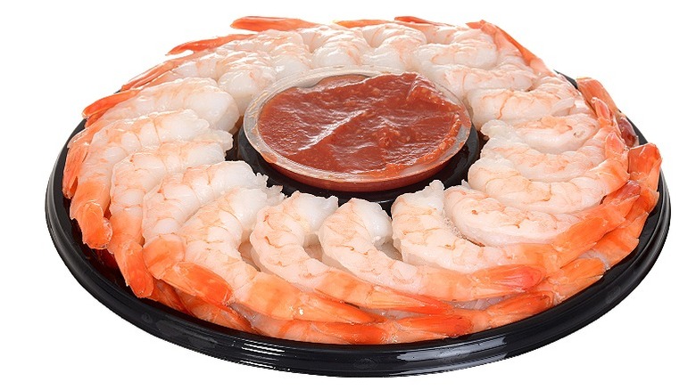 a platter with shrimp, tail-on, with a tub of sauce in the center