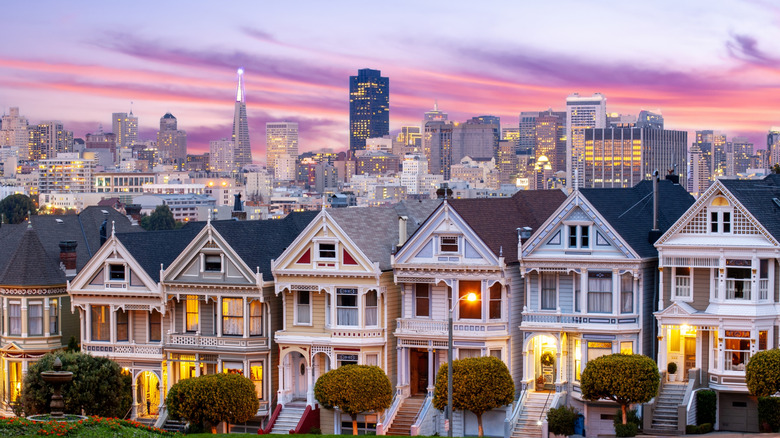 Houses in row and San Francisco city skyline in background at sunset