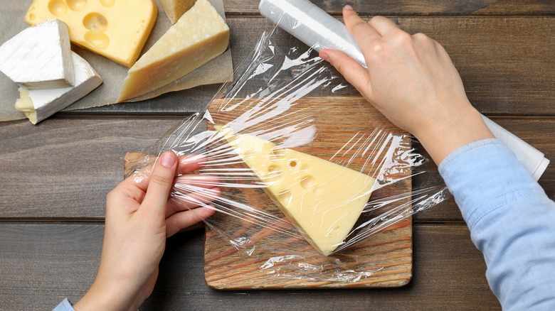 Person wrapping cheese in plastic