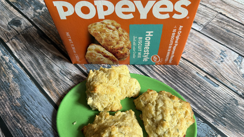 Popeyes Homestyle Biscuits box and some biscuits made from it on a green plate