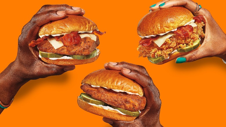 hands holding Popeyes' chicken sandwiches