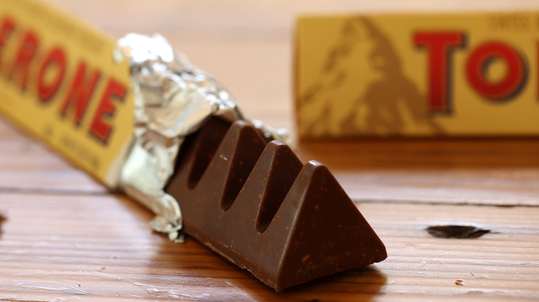 A partially unwrapped Toblerone bar on a wood table