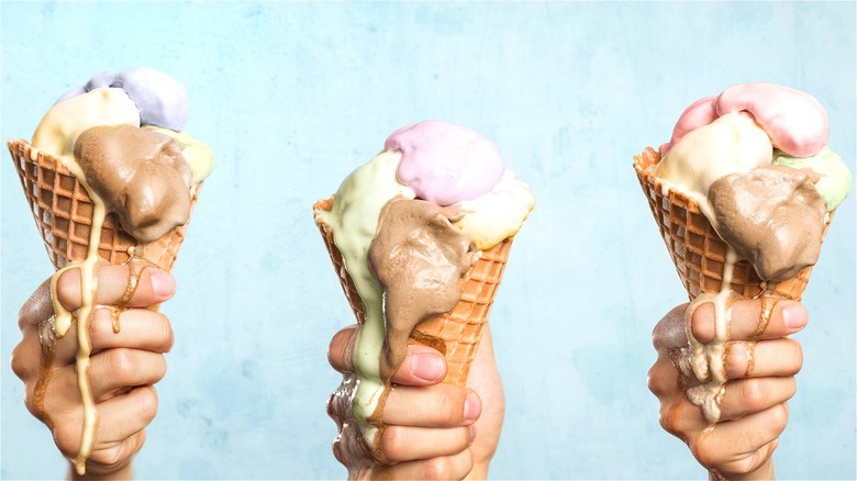 Hands holding dripping ice cream cones 