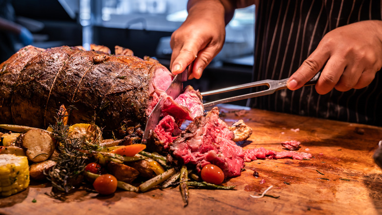 A chef shown cutting a beef roast prime rib.