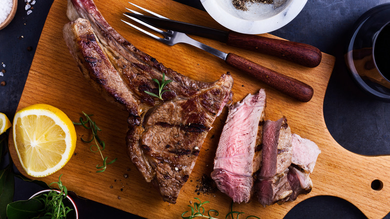 Steaks from a rib roast served on a wooden tray.