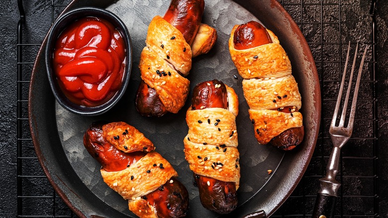 Pigs in blankets with puff pastry on a plate with ketchup side